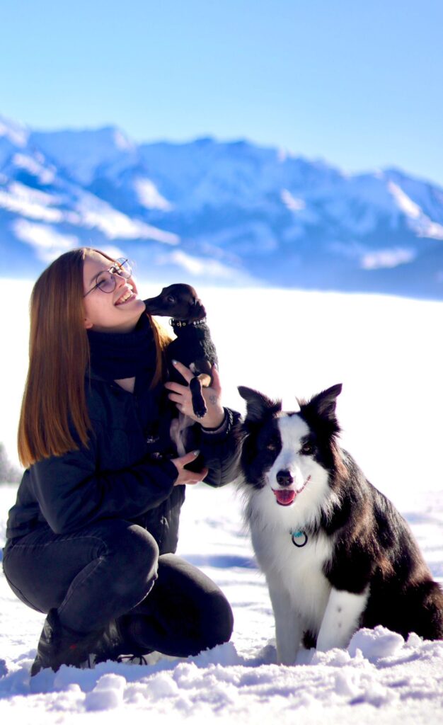 une jeune femme, marie, la responsable du salon, assise dans la neige avec ses chiens